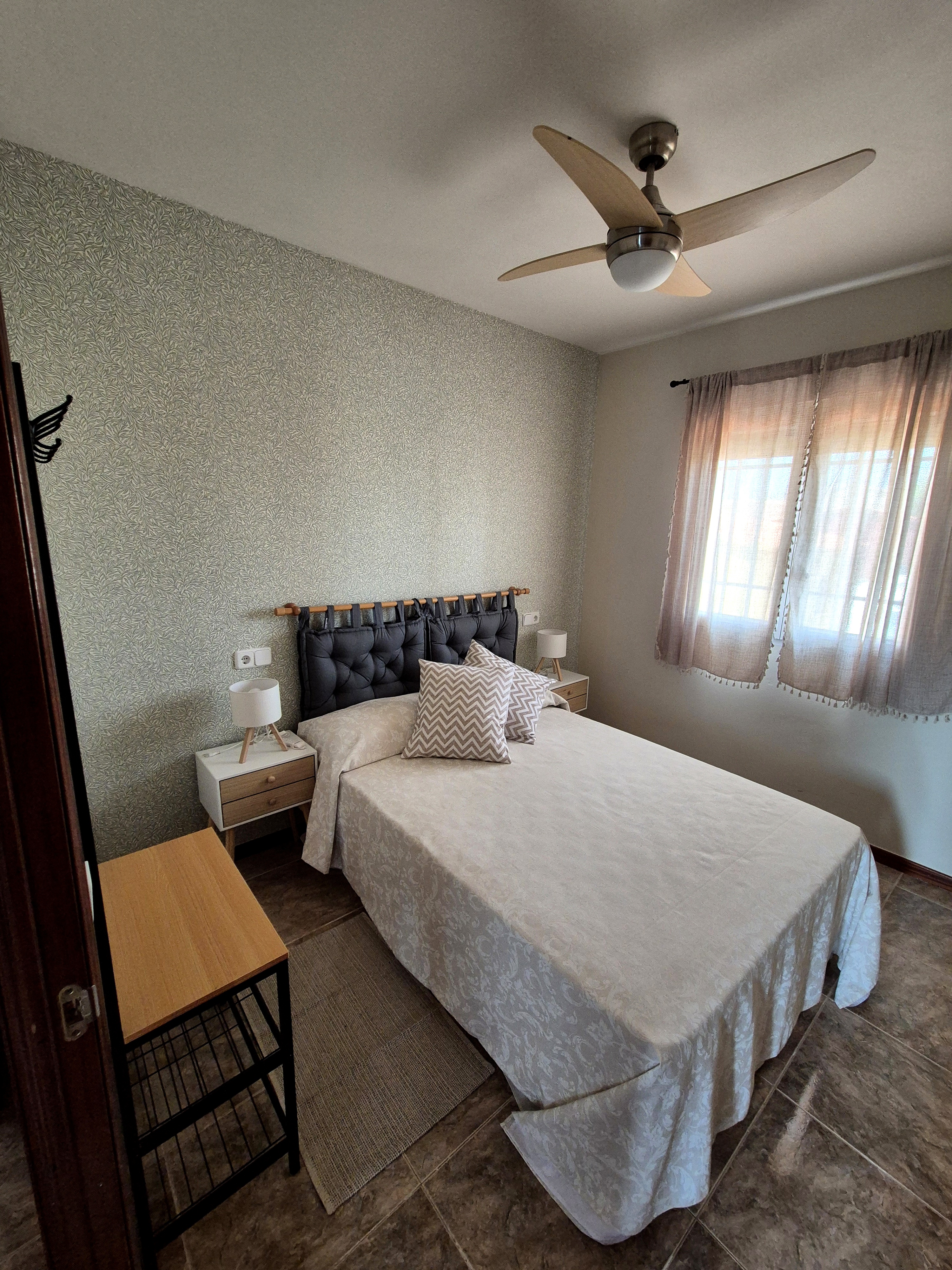 Cama pequeña doméstica con ropa de cama blanca y recargada, dos mesitas de noche pequeñas para fluorescer almohadas blanqu...