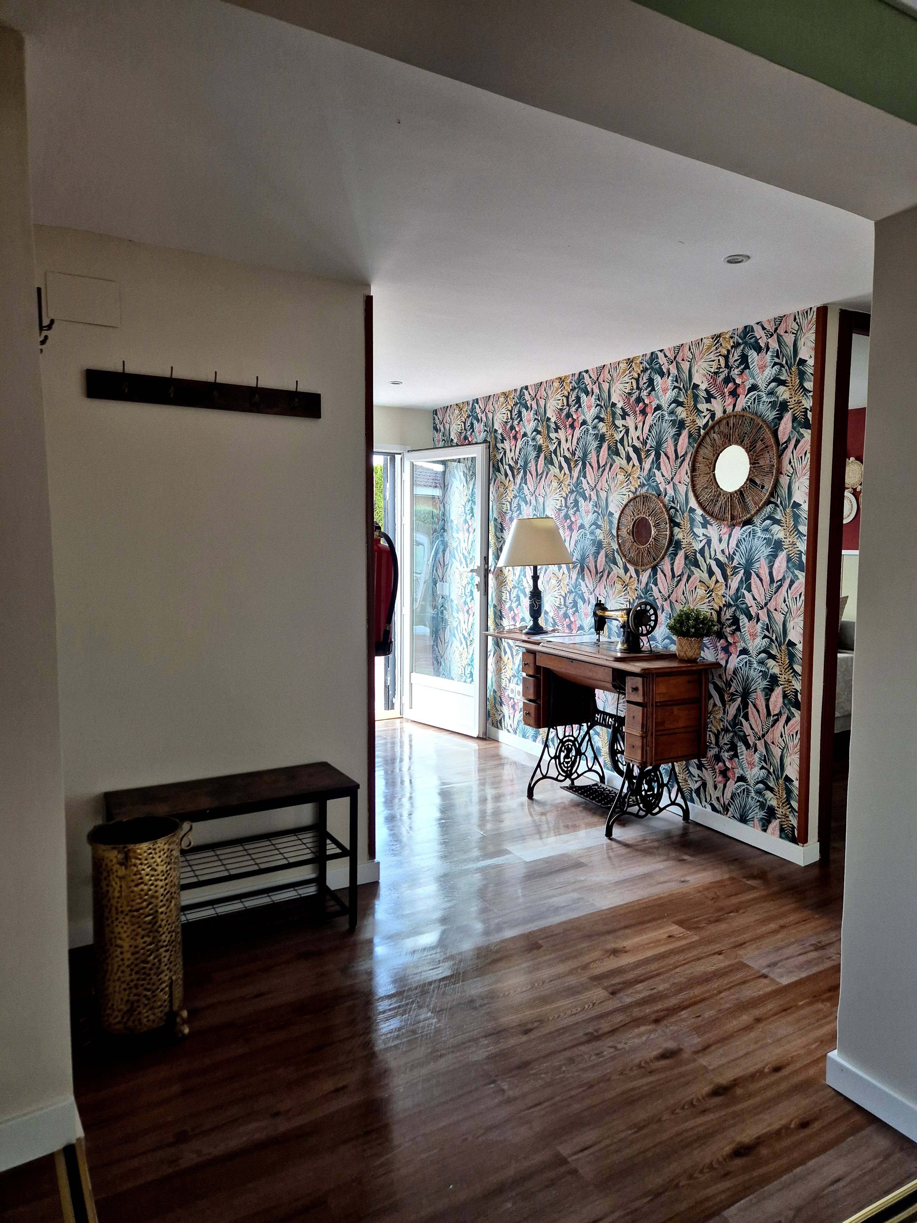 La imagen muestra el interior de casa, con el vestíbulo tras una puerta. A lo lejos, podemos ver una habitación con un esp...